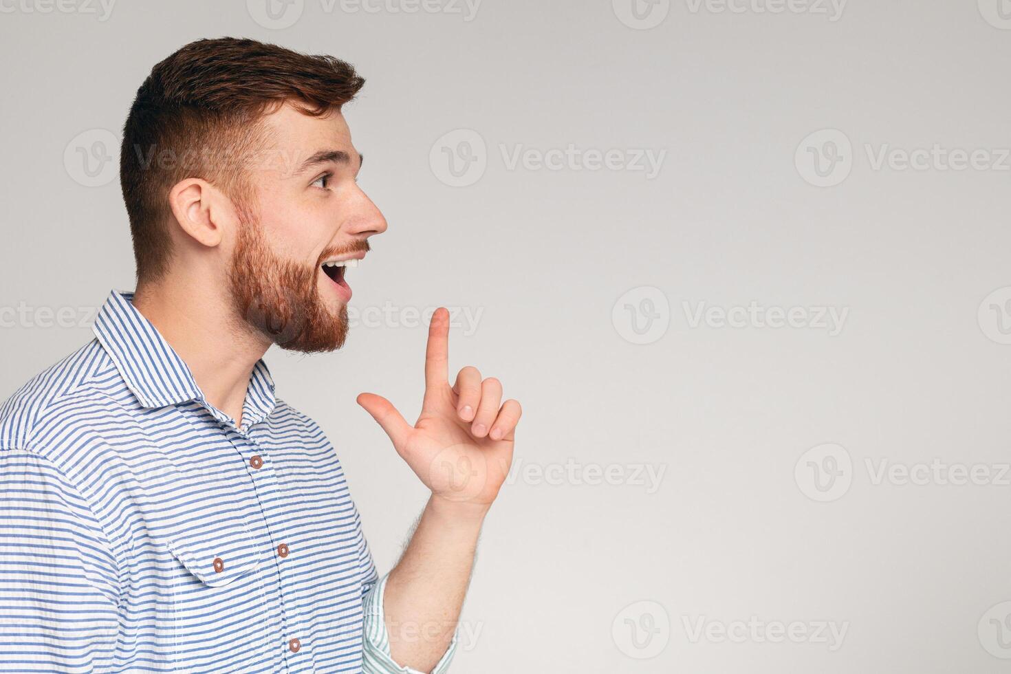 Young excited man having good idea and feeling happy about that, grey studio background, panorama, copy space photo