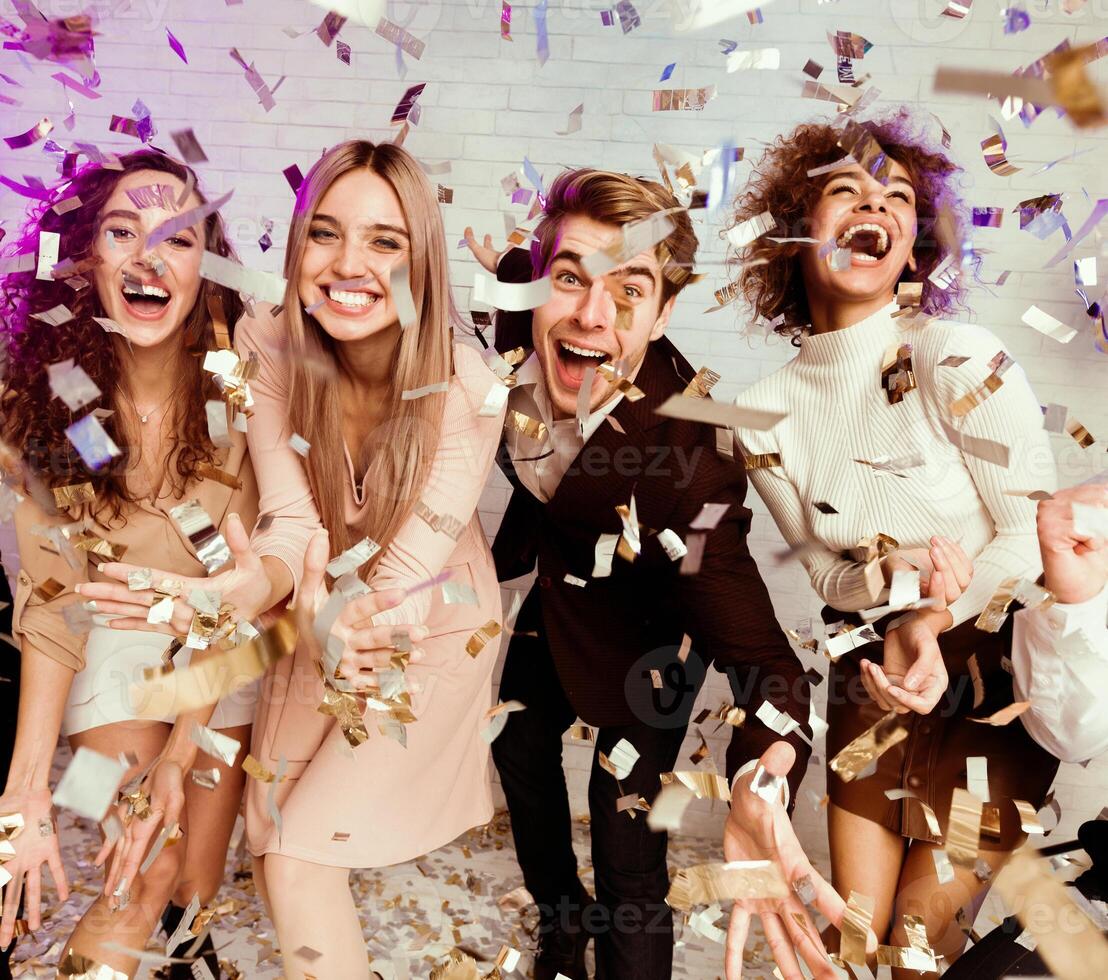 Party Concept. Multiethnic Friends Enjoying Life Partying And Dancing Showered With Falling Confetti Indoor photo