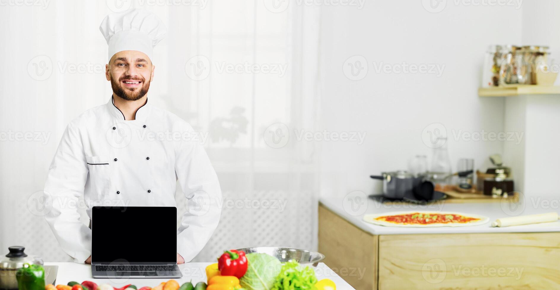 Excited Male Chef Showing Laptop Computer Empty Screen Cooking Standing In Kitchen. Mockup photo