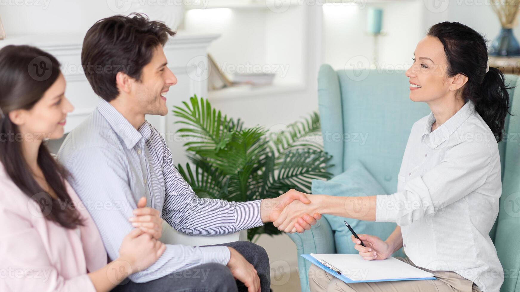 Surrounded by a calm office ambiance, a young couple receives guidance from a woman psychologist, aiming to deepen understanding and resolve conflicts. photo