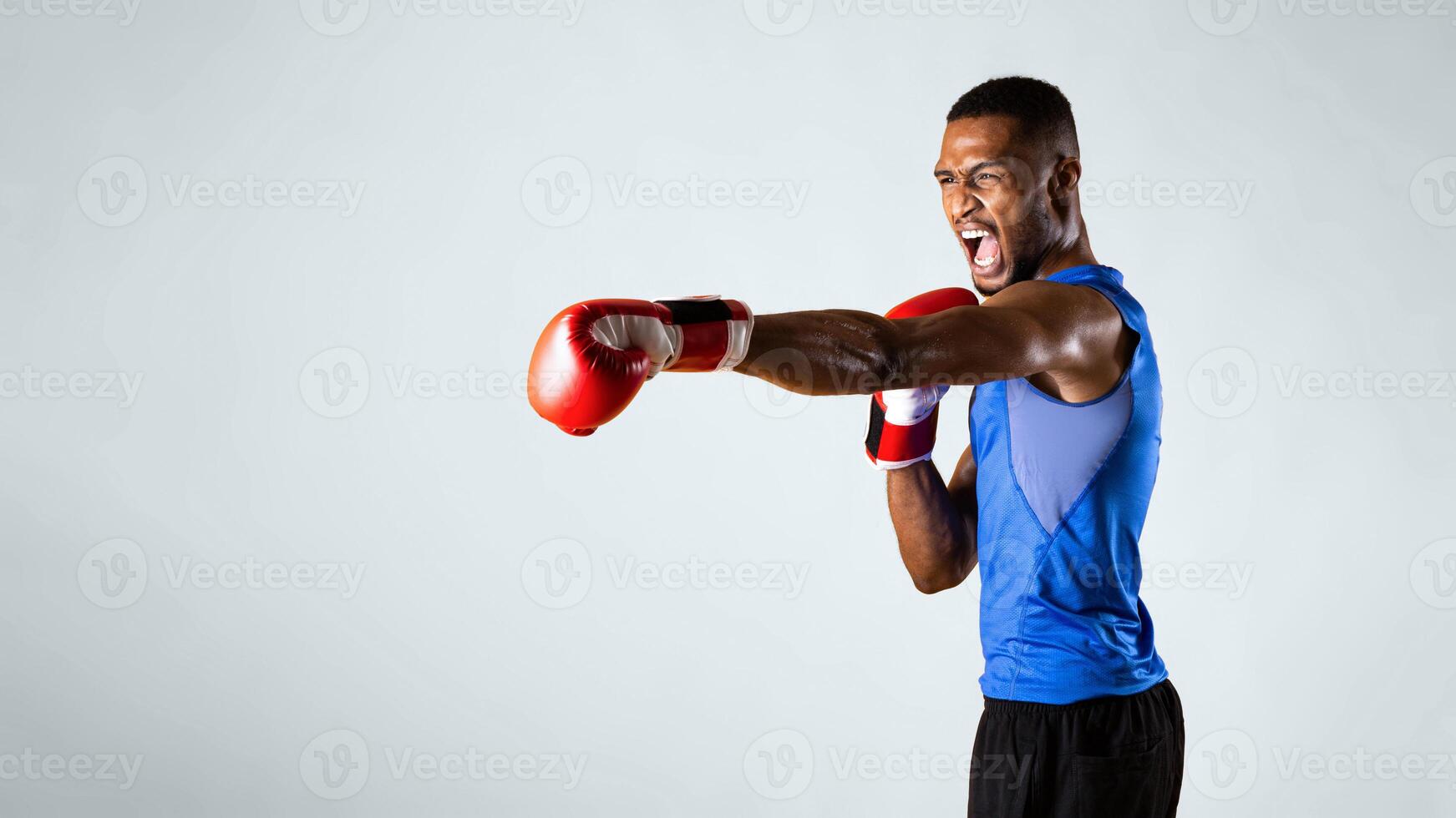 Ready For Fight. Aggressive black man practicing boxing punches in gloves, yellow background. Panorama, copyspace photo