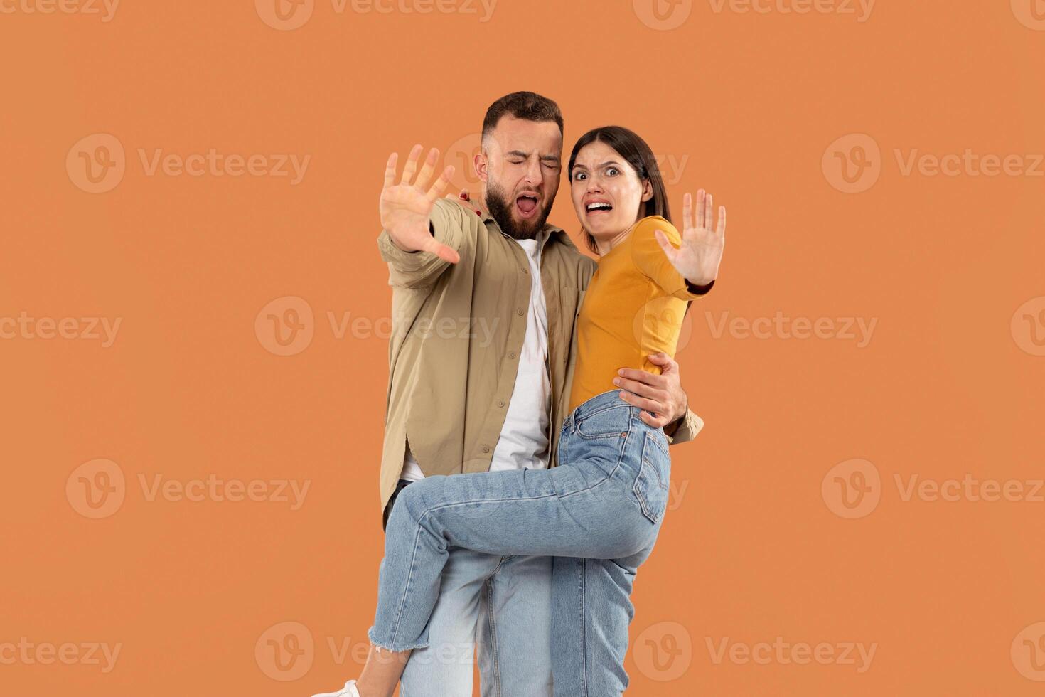 Displeased young couple isolated on orange studio background look at camera denying bad sale offer, dissatisfied unhappy man and woman make gesture say no reject refuse proposal or suggestion photo