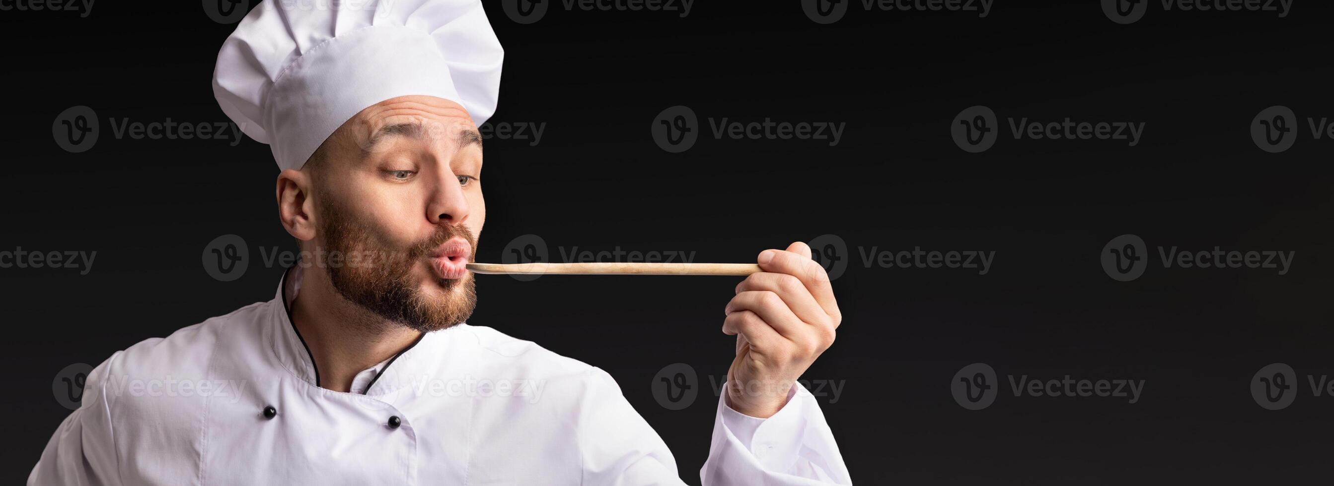 Gourmet. Chef Man Holding Spoon Tasting Food Standing On Black Studio Background. Panorama photo