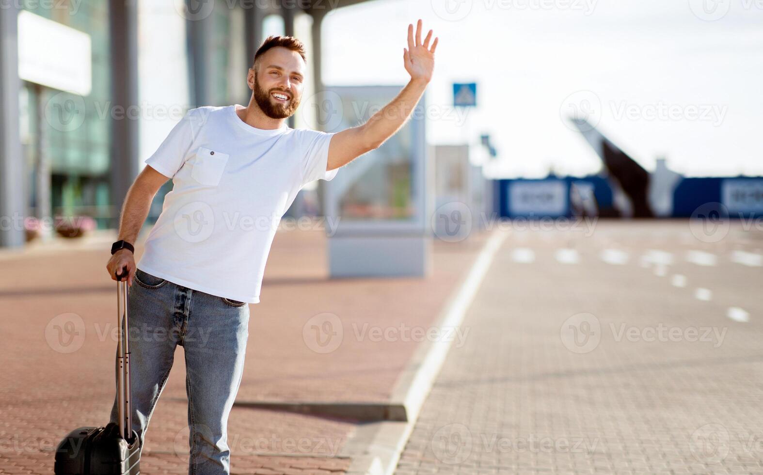 Arriving Home Concept. Tourist trying to catch taxi, waving and standing with baggage, copyspace photo