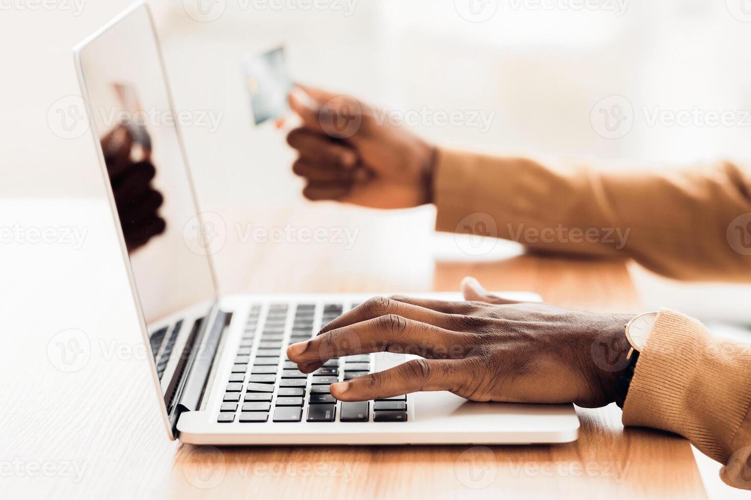 Close-up Of Black Man Filling Credit Card Information Using Laptop. Selective focus on hands, free space photo