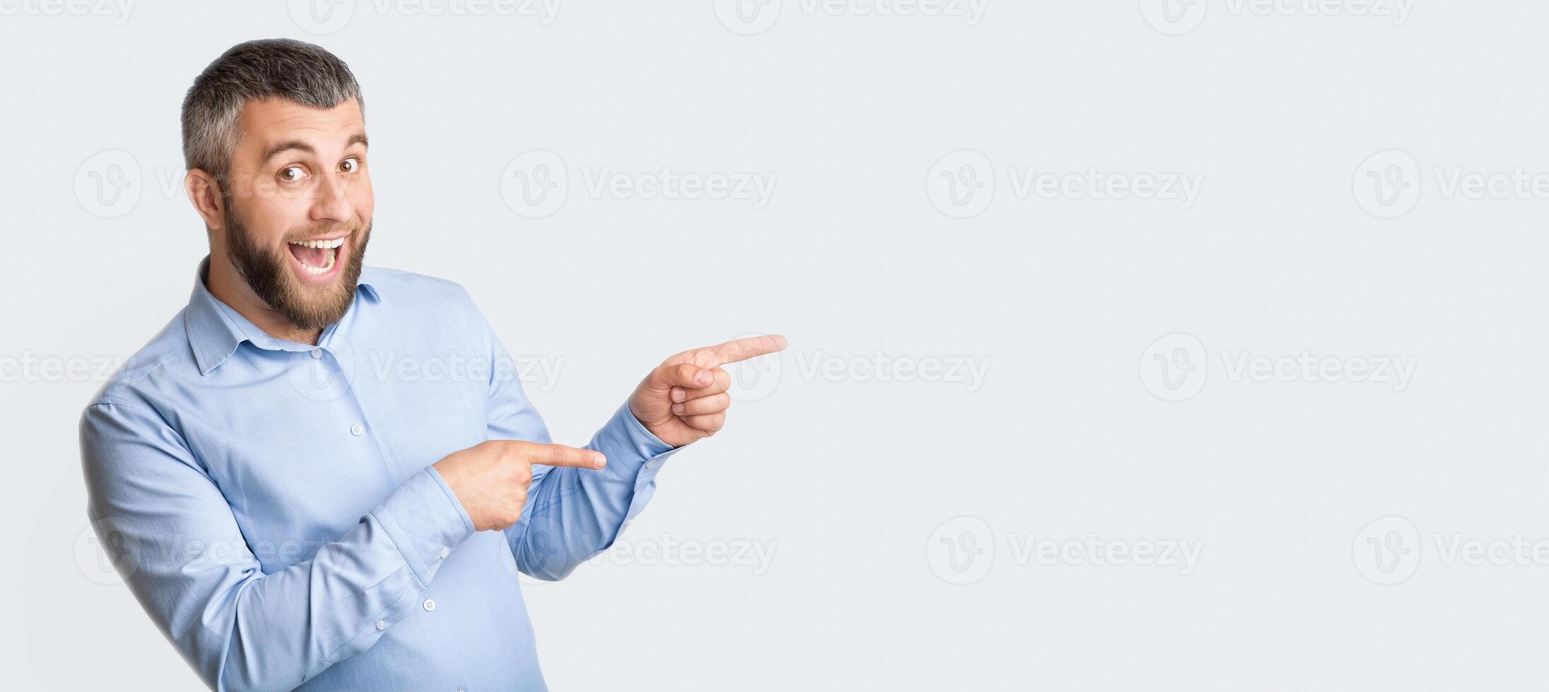 A man wearing a blue shirt is pointing at an unseen object in the distance. He appears to be directing attention or indicating a specific direction, panorama with copy space photo