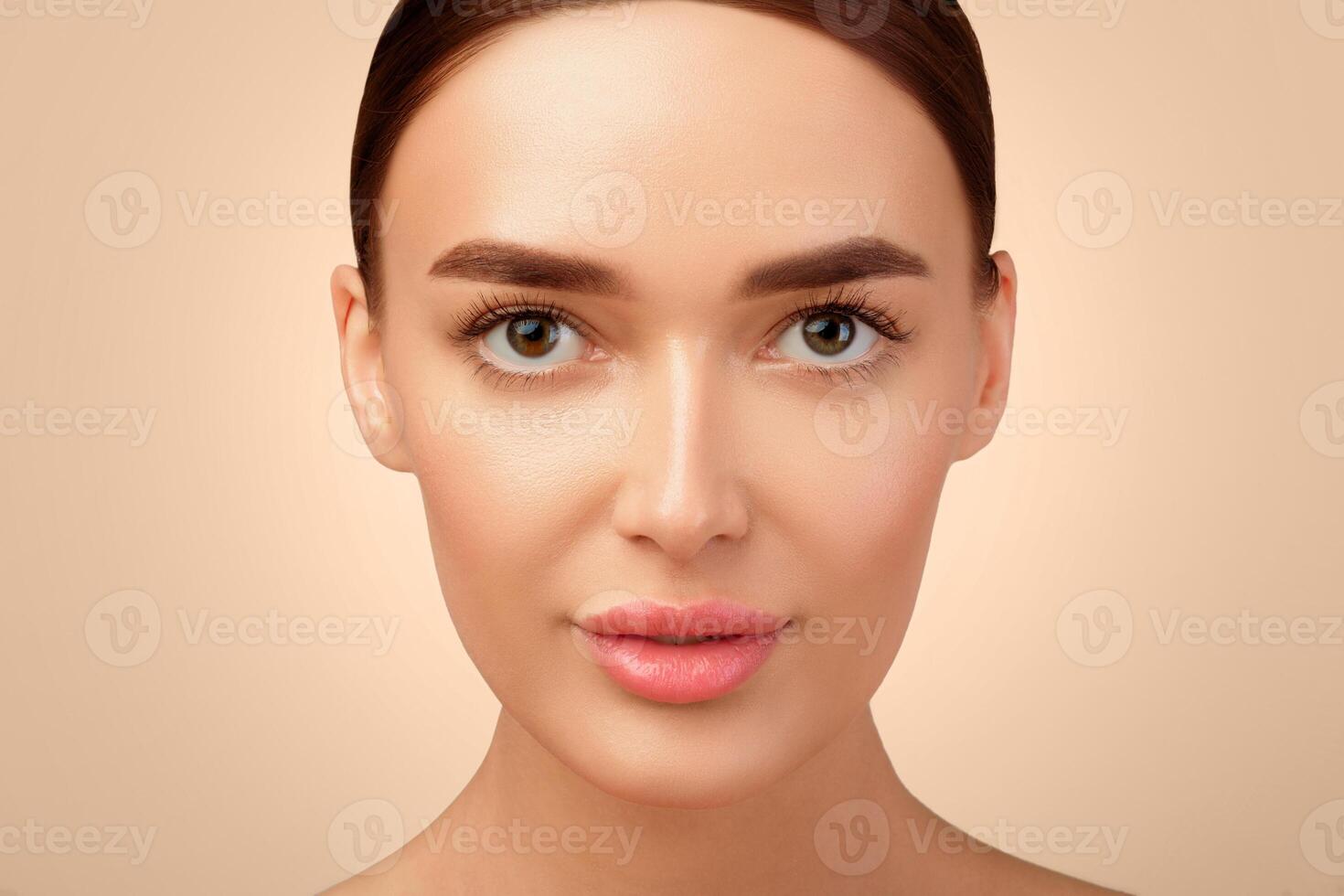 Facial Skincare And Makeup. Closeup Portrait Of Attractive European Woman With Perfect Smooth Skin, Looking At Camera Posing On Light Gray Background In Studio. Female Beauty Concept photo