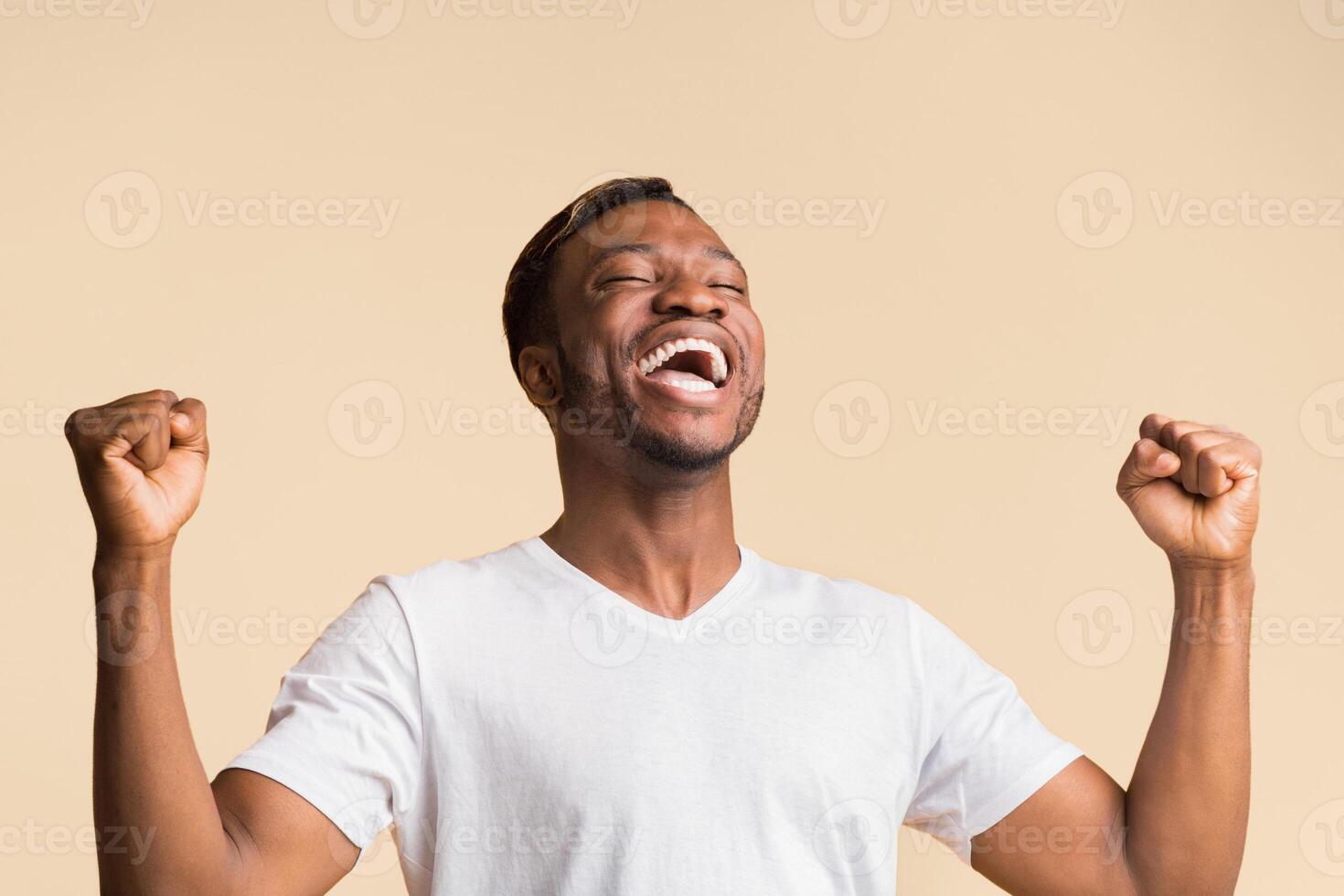 Winner. Happy Black Man Screaming In Delight And Shaking Fists Standing Over Yellow Studio Background. photo