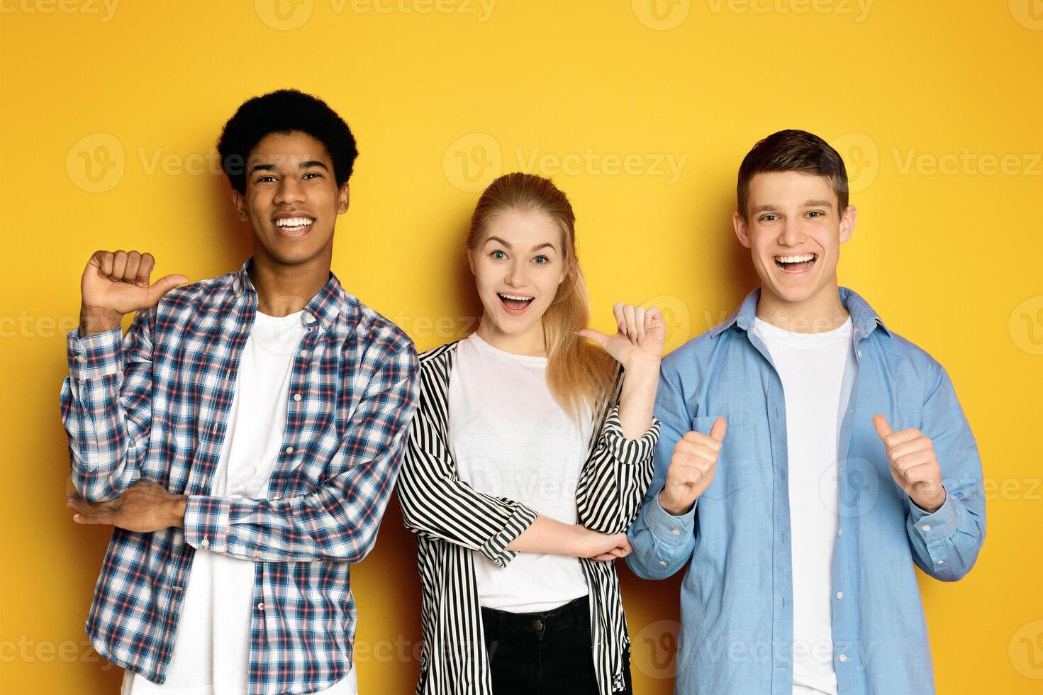 Three multiethnic teenagers are standing side by side, each with a beaming smile and giving a thumbs-up gesture photo