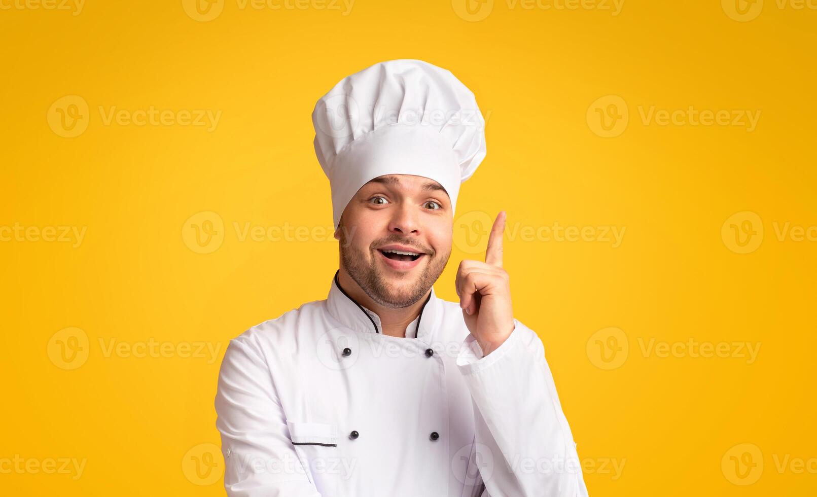Great Recipe. Excited Chef Man Pointing Finger Up Having Idea Of A New Dish Standing On Yellow Studio Background. Panorama photo
