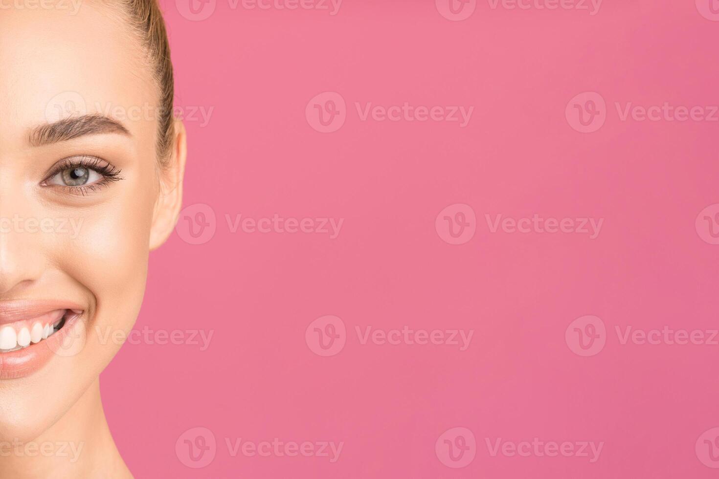 This image features a close up of a woman face. Only half of her face is visible, and her mouth is slightly open in a wide smile. Her eyes are closed and her teeth are perfectly white, copy space photo