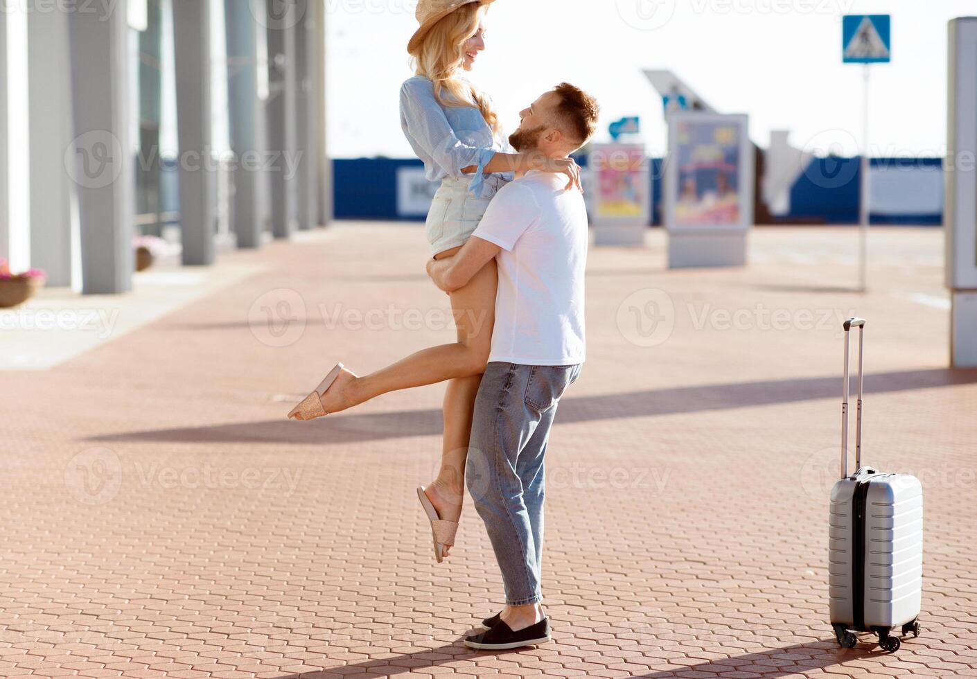 Couple meeting after long time, hugging near airport building, free space photo