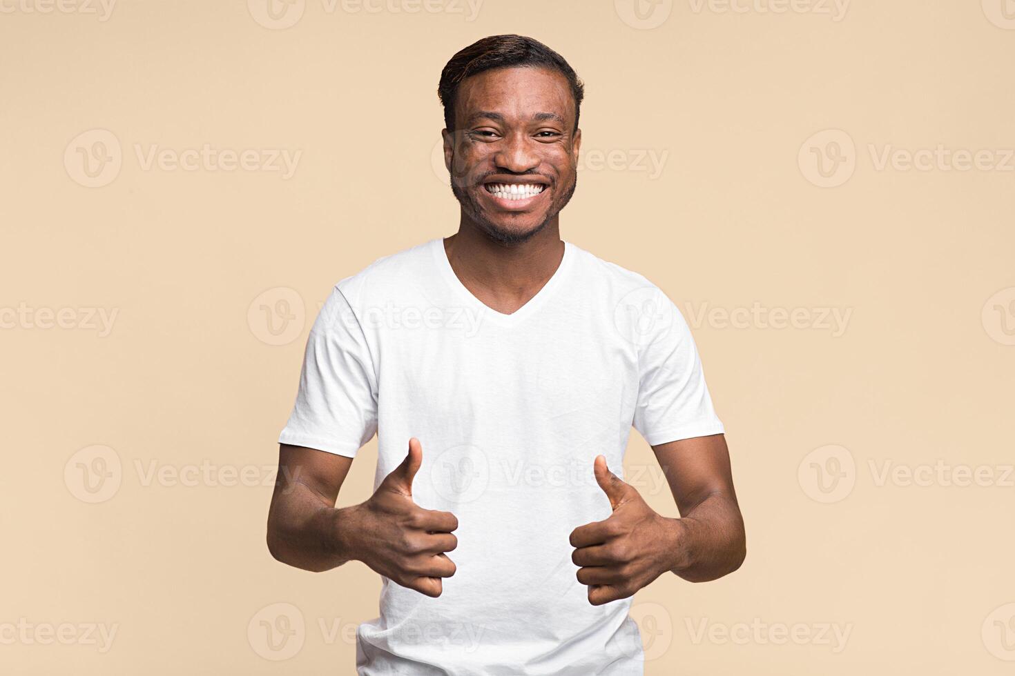 Cheerful Afro Man Gesturing Thumbs Up With Both Hands Posing Over Yellow Studio Background. Like Concept. photo