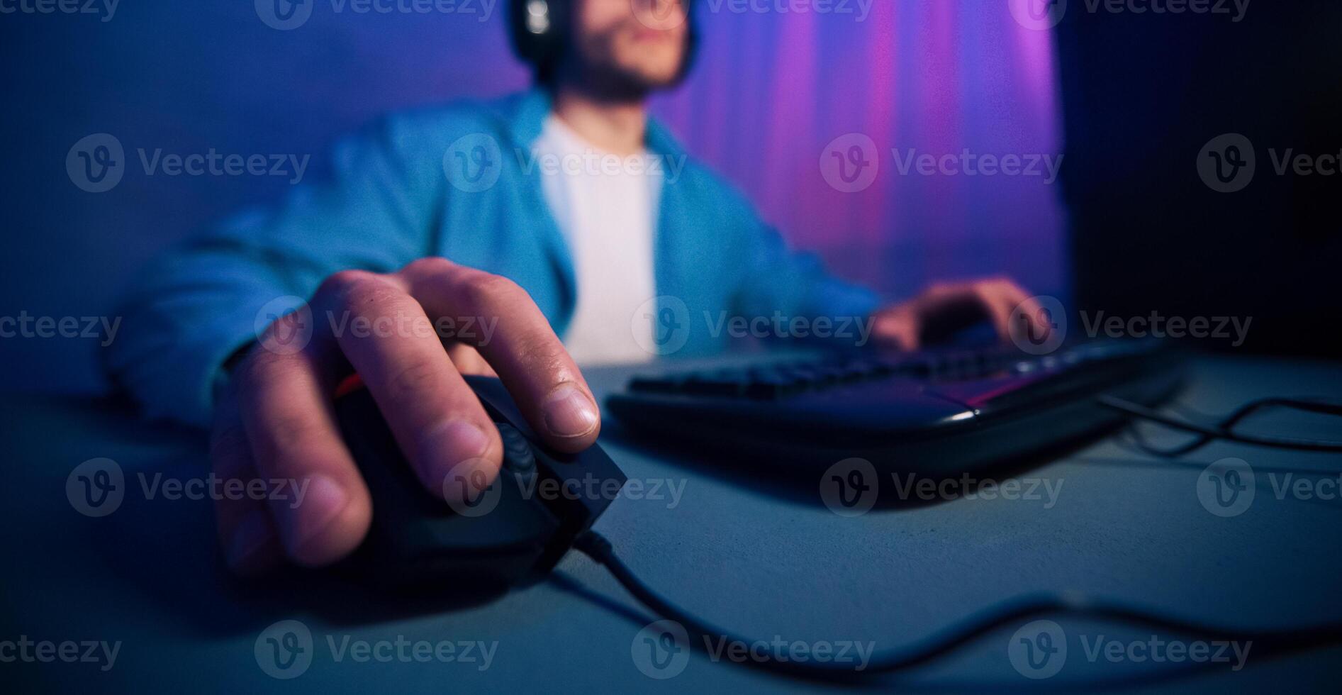 A close-up image of a gamers hand using a computer mouse while playing a game on their desktop. The focus is on the hand and the mouse, cropped photo