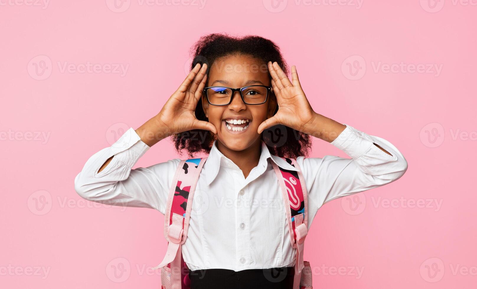 Hey. Joyful Schoolgirl Holding Hands Near Face Announcing Back-To-School Smiling To Camera Over Yellow Background. Studio Shot photo