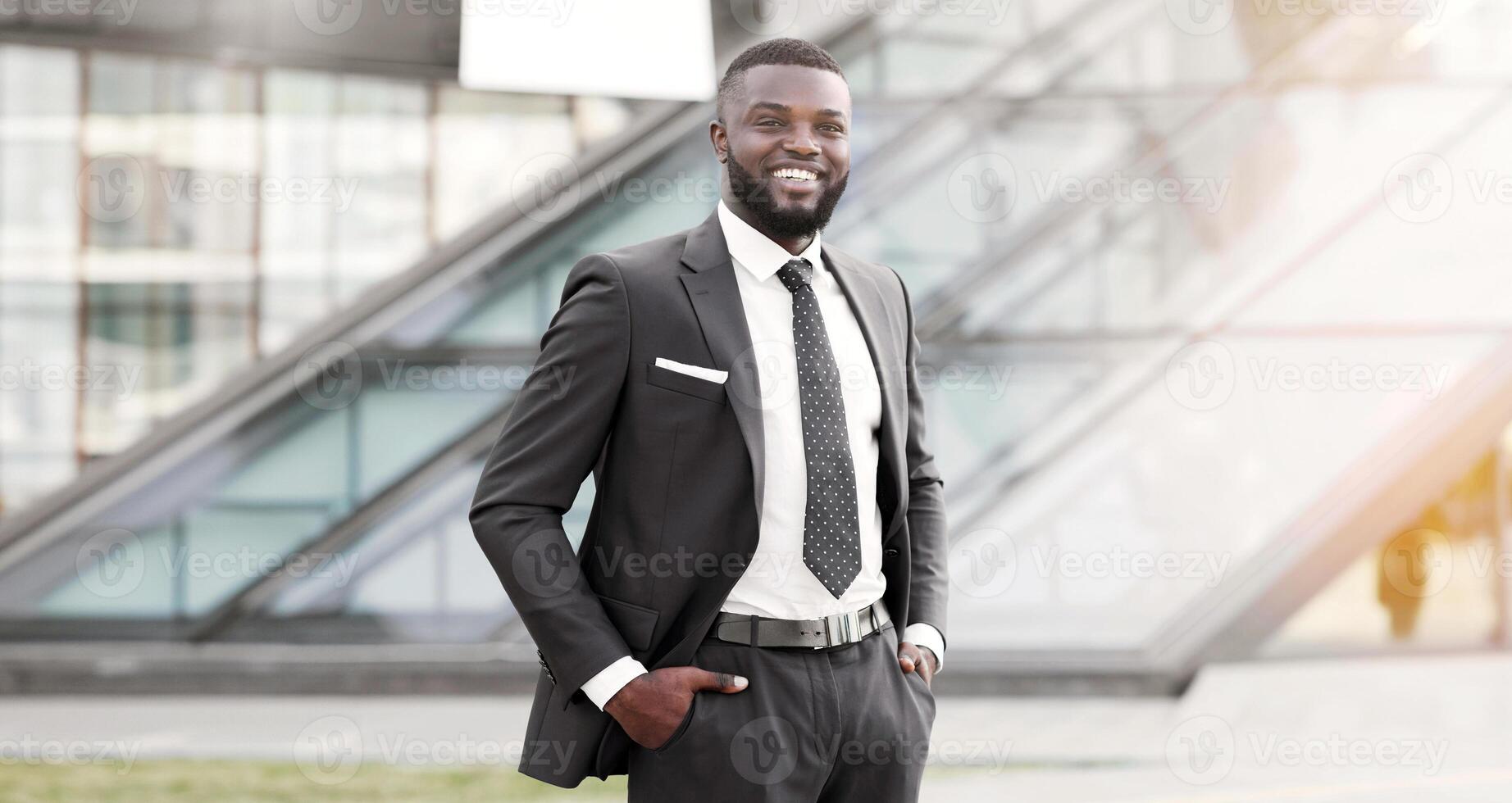 Tremendous Career. Positive African American Businessman Standing Keeping Hands In Pockets In Urban Area. Copy Space, Shallow Depth. photo