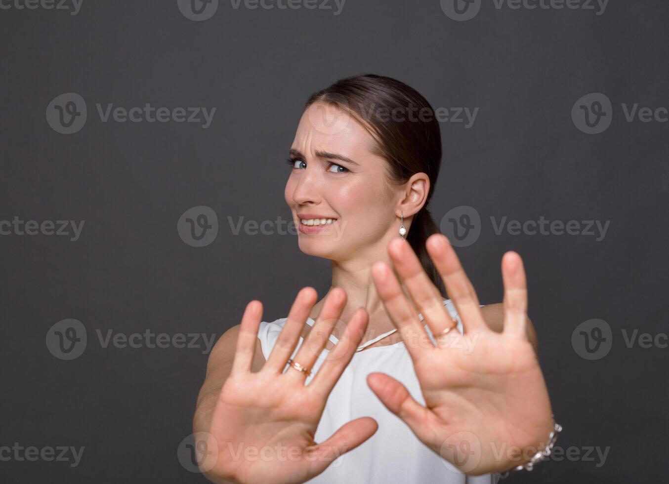 Attractive woman saying thanks but no. Beautiful girl denying proposal, making stop gesture with her hands, looking at camera photo