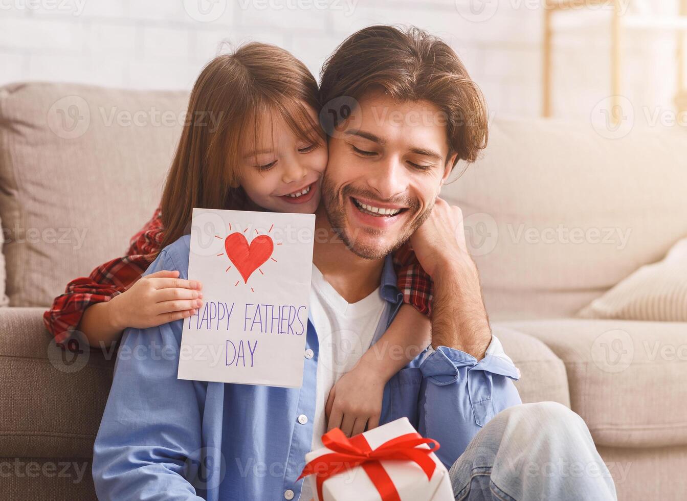 Happy Father Day, sweet girl surprising her daddy with gift and self-made card, happy dad holding gift box, copy space photo