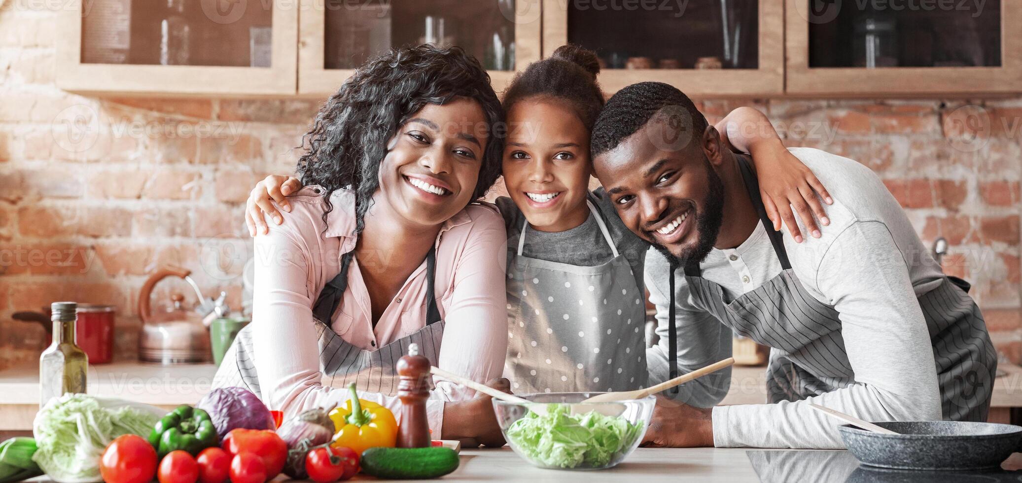 Happy african family embracing at kitchen while making healthy dinner, copy space photo