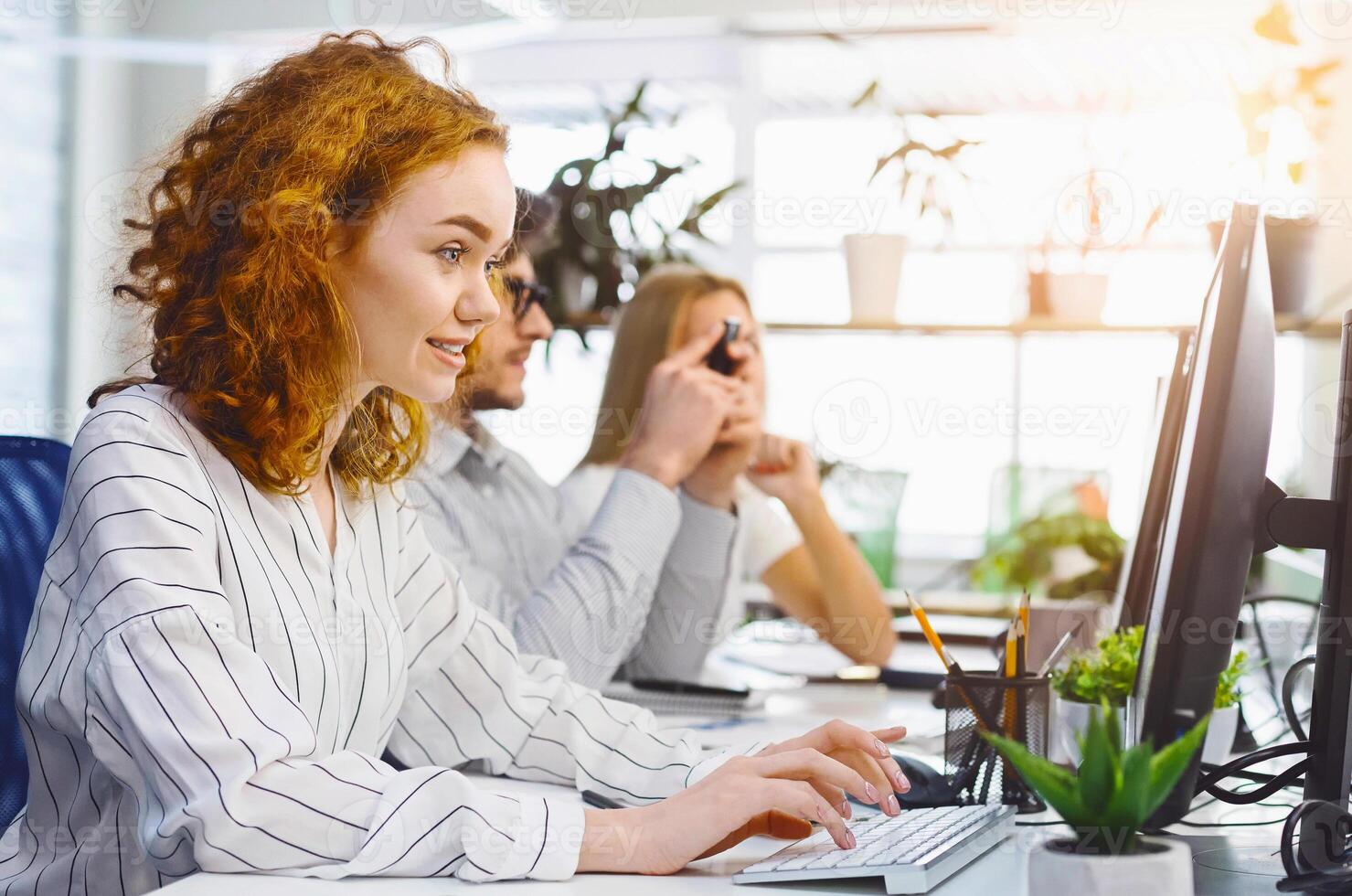 Young busy staff of employees working on computers, sitting at desk in modern office room, free space photo