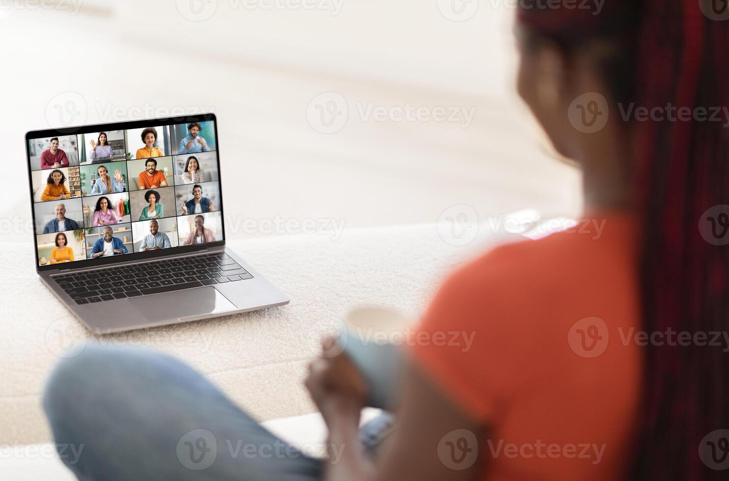 A woman sits in front of an open laptop, participating in a conference meeting. She is engaged in the meeting and appears to be listening intently to the speakers. photo