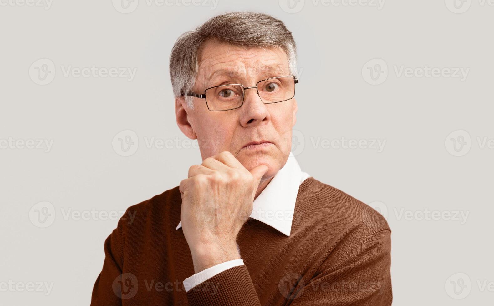 Serious Elderly Man Posing Looking At Camera Touching Face On Gray Background. Studio Shot photo