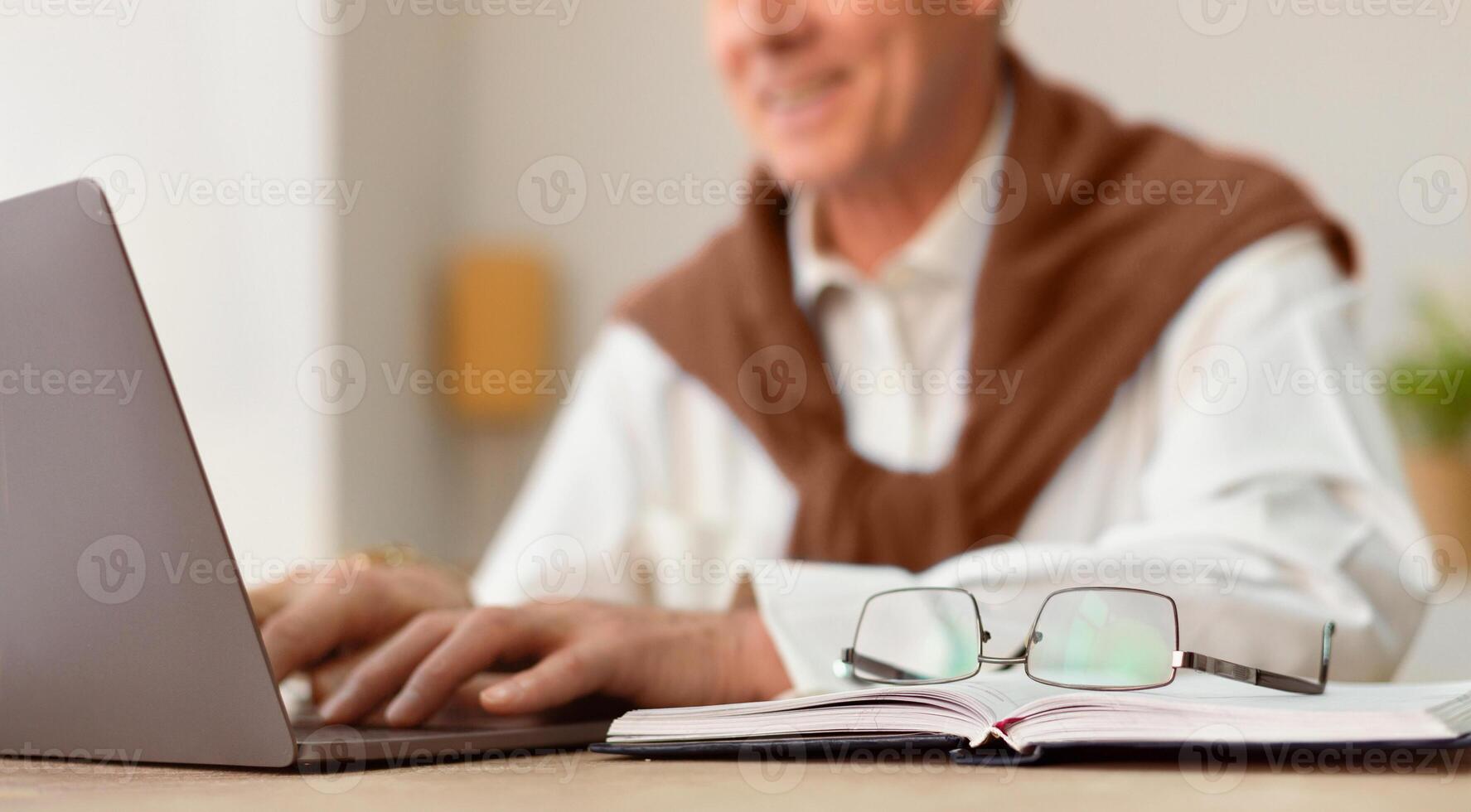 Cheerful Elderly Man Working On Laptop Computer Sitting In Modern Office. Cropped, Selective Focus photo