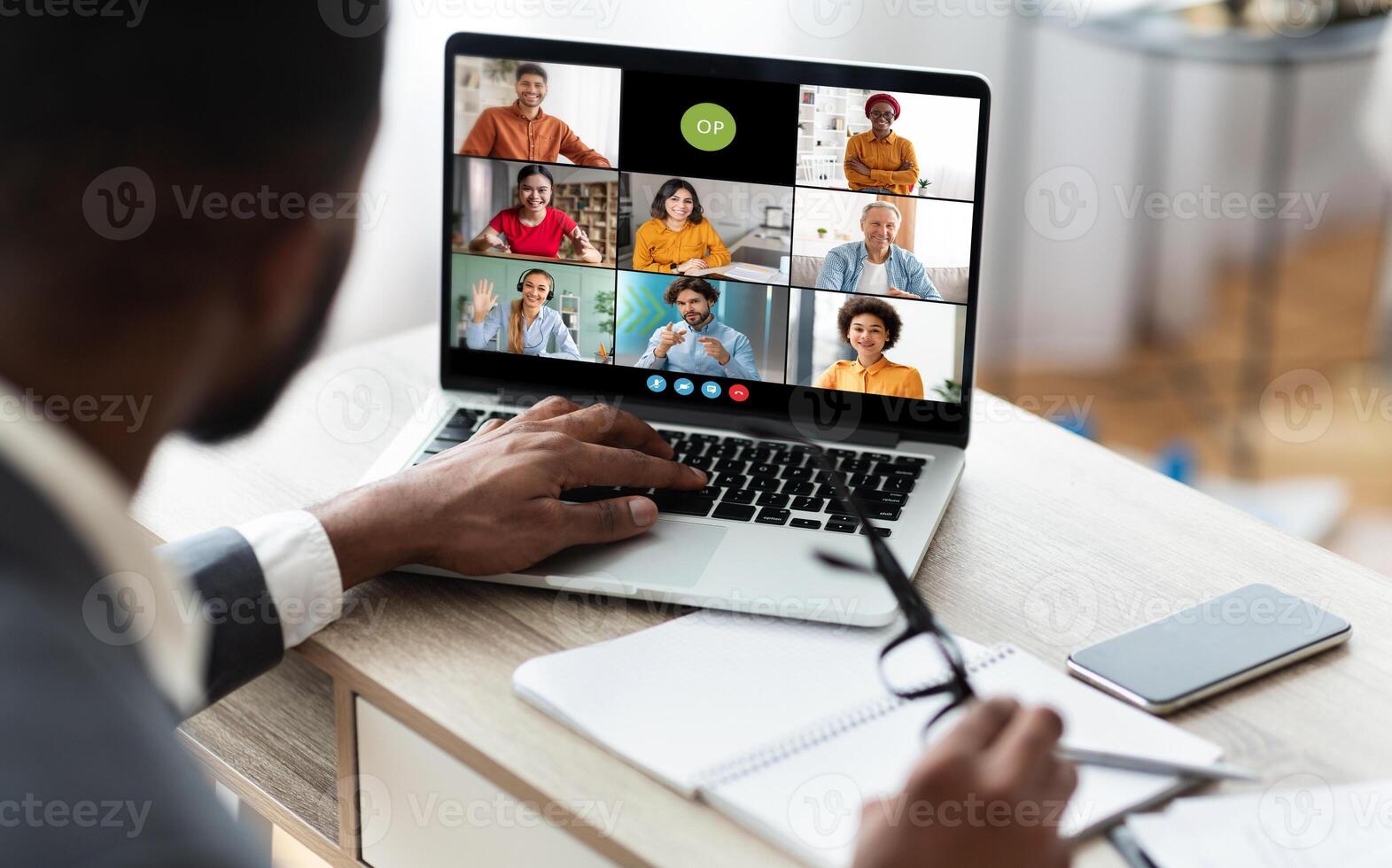 African American businessman sits at his desk and participates in a conference meeting on his laptop. He is listening intently to the speakers on the screen photo
