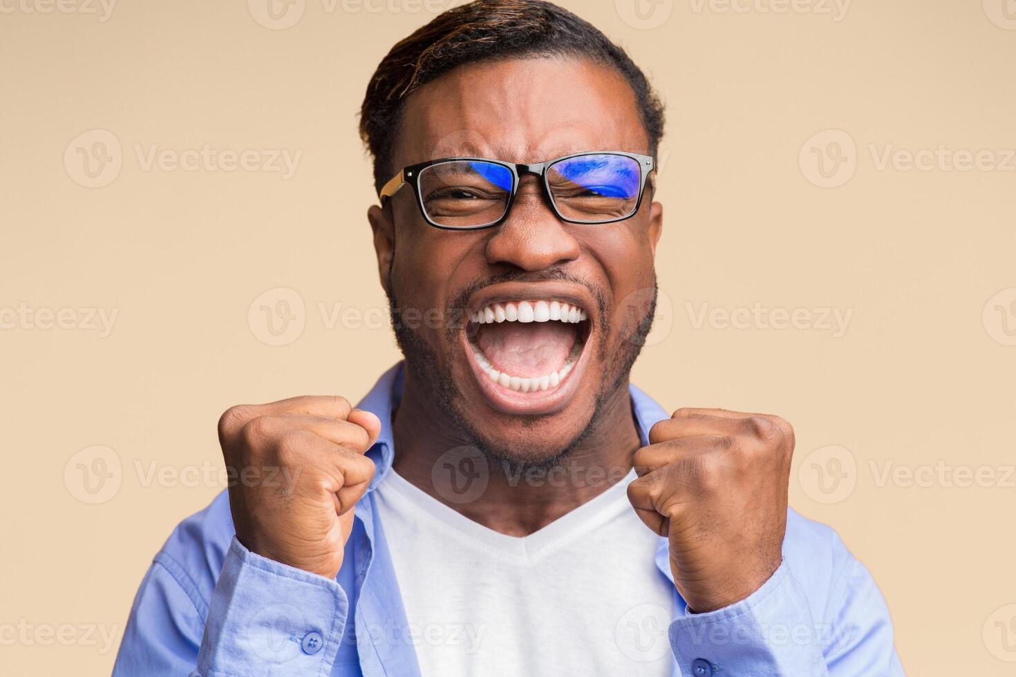 Yes. Emotional Black Man Screaming And Shaking Fists Rejoicing Victory And Success Standing On Orange Background. Studio Shot photo