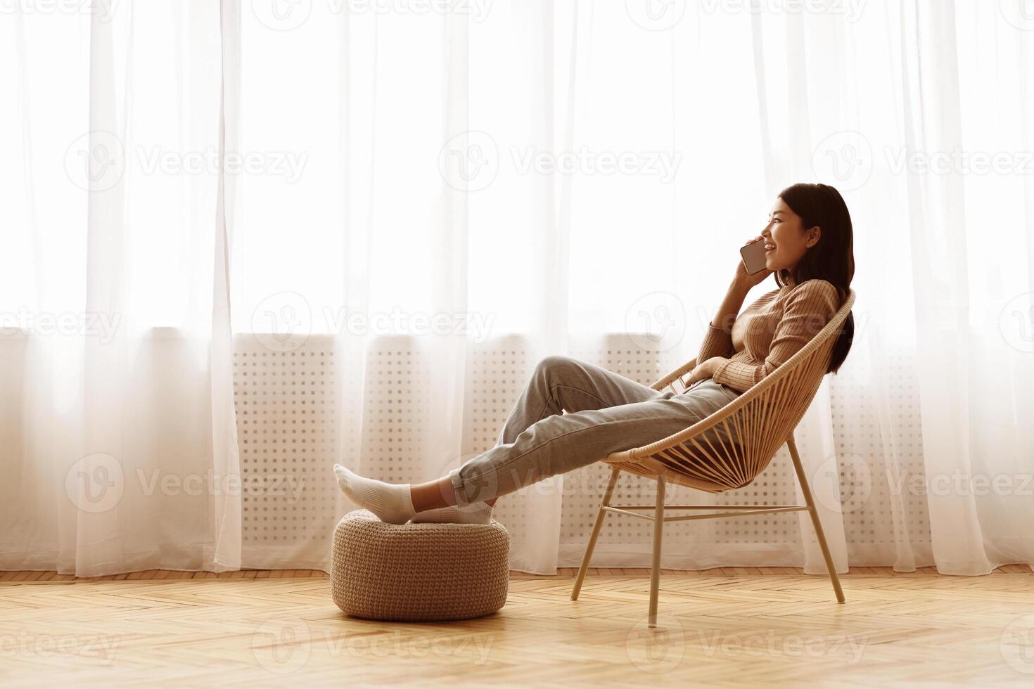 Relaxed Girl Talking on Phone near Window, Sitting on Chair and Resting, Free Space photo