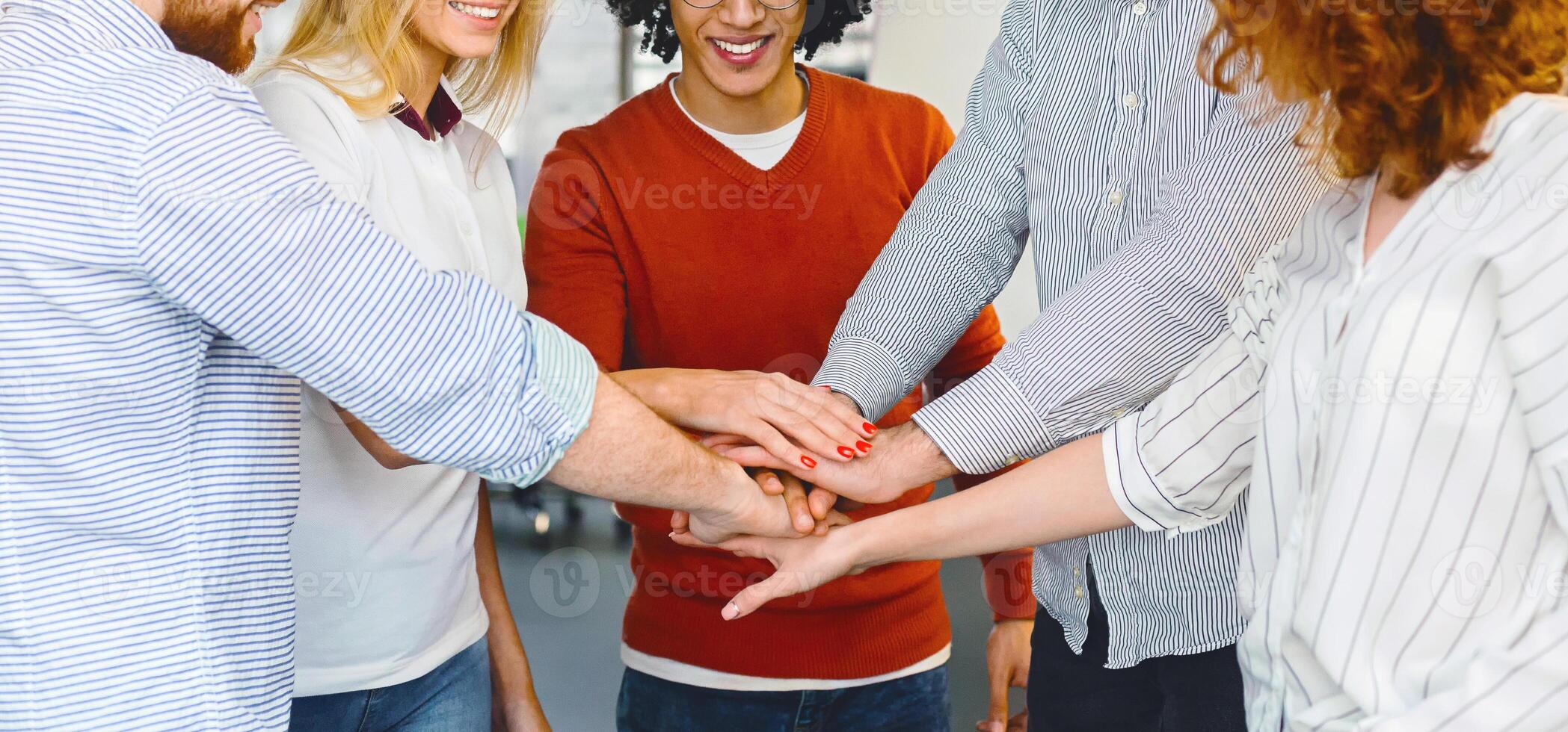 A diverse group of individuals standing together in a circle, each holding hands with the person next to them. They are united in a gesture of unity and solidarity, cropped, panorama photo