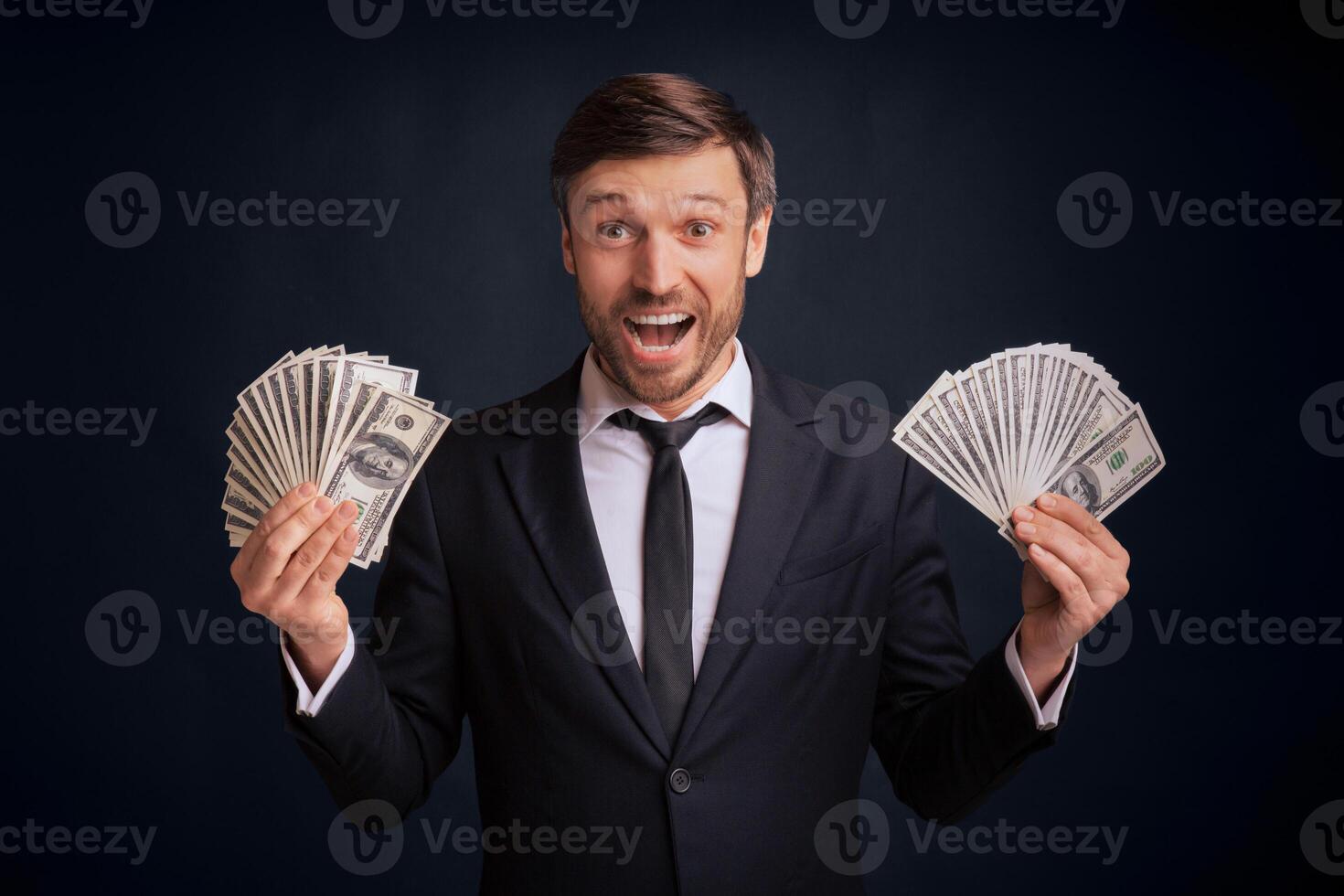 Business Success And Wealth. Gladful Businessman Holding Money Over Black Background In Studio. photo