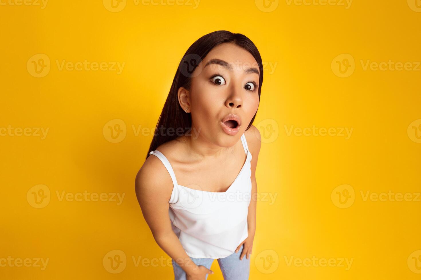 Wow. Surprised Asian Lady With Funny Expression Posing On Yellow Background, High Angle View photo