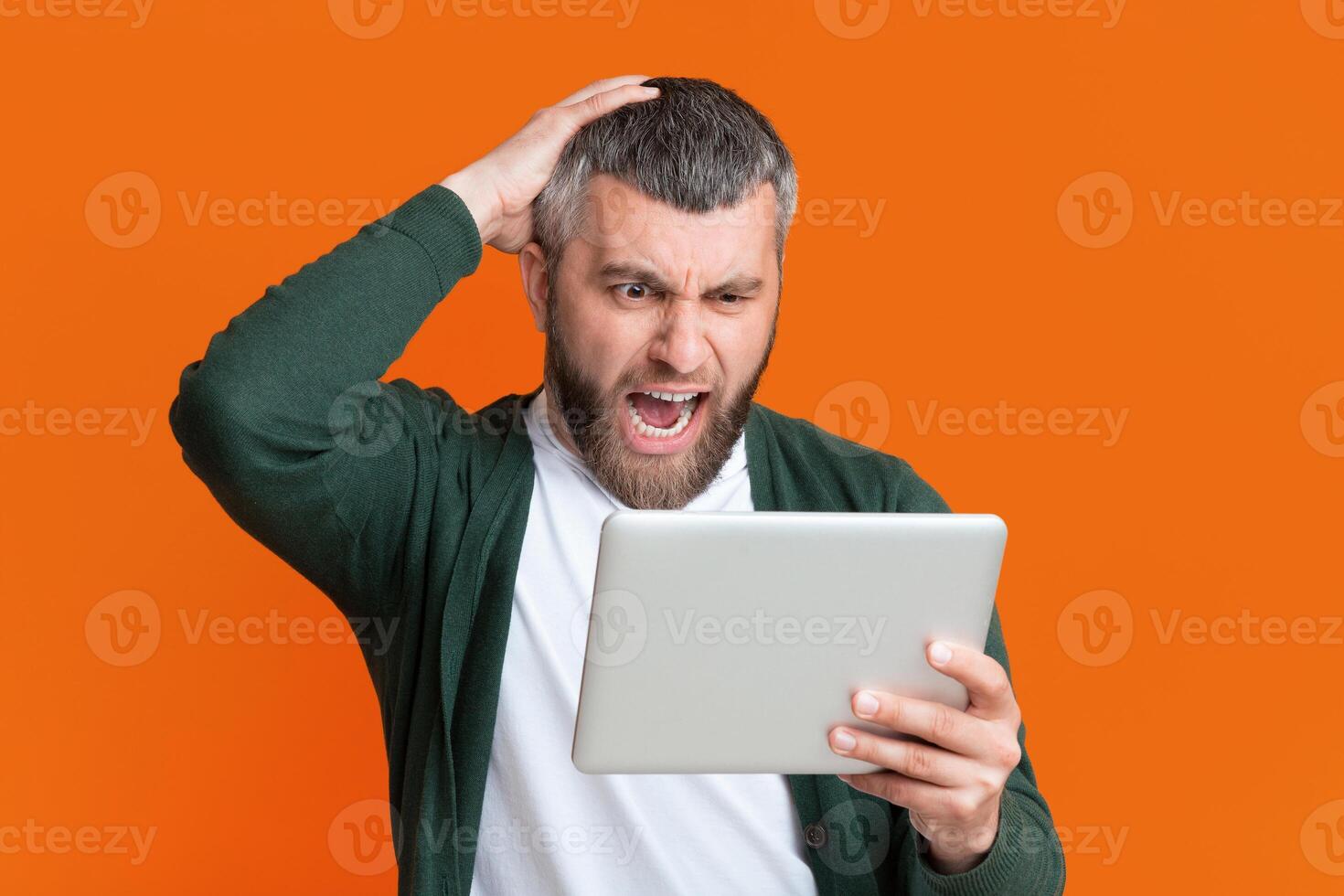 A man with a surprised look on his face as he holds a tablet in his hands, possibly reacting to unexpected news or information displayed on the device. photo