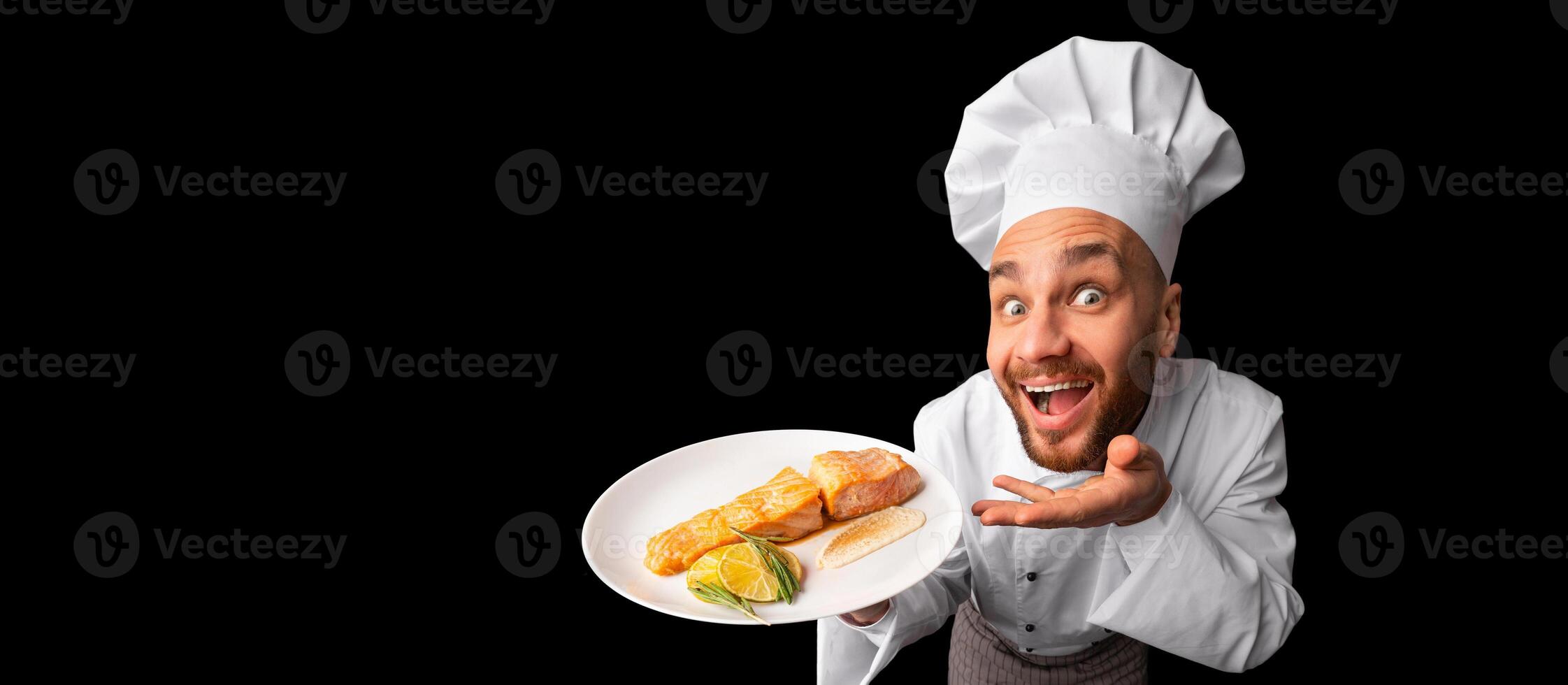 Funny Chef Man Holding Plate Serving Fish Dish Standing On Black Studio Background. Panorama, High-Angle Shot photo