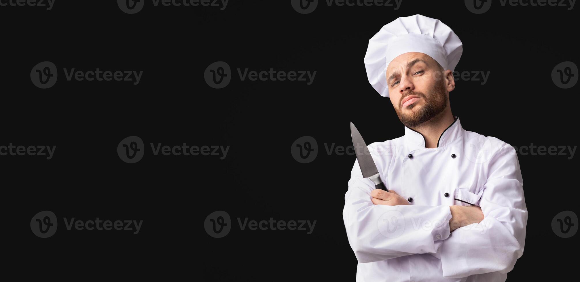 Professional Chef Posing With Knife Looking At Camera Standing Over Black Studio Background. Panorama, Empty Space photo