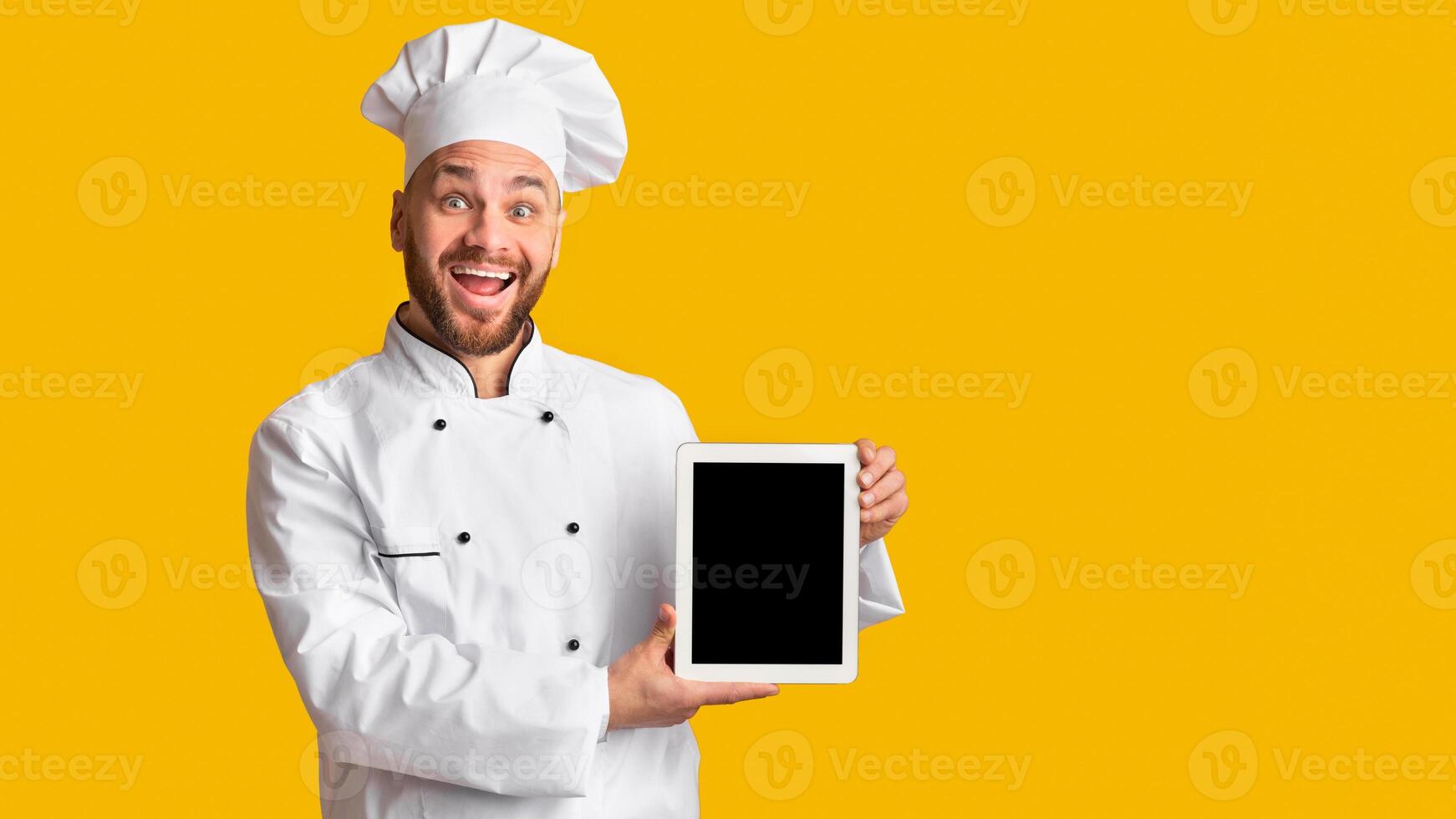 Cooking Food App. Joyful Male Chef Holding Digital Tablet Showing Blank Screen Standing Over Yellow Studio Background. Mockup photo