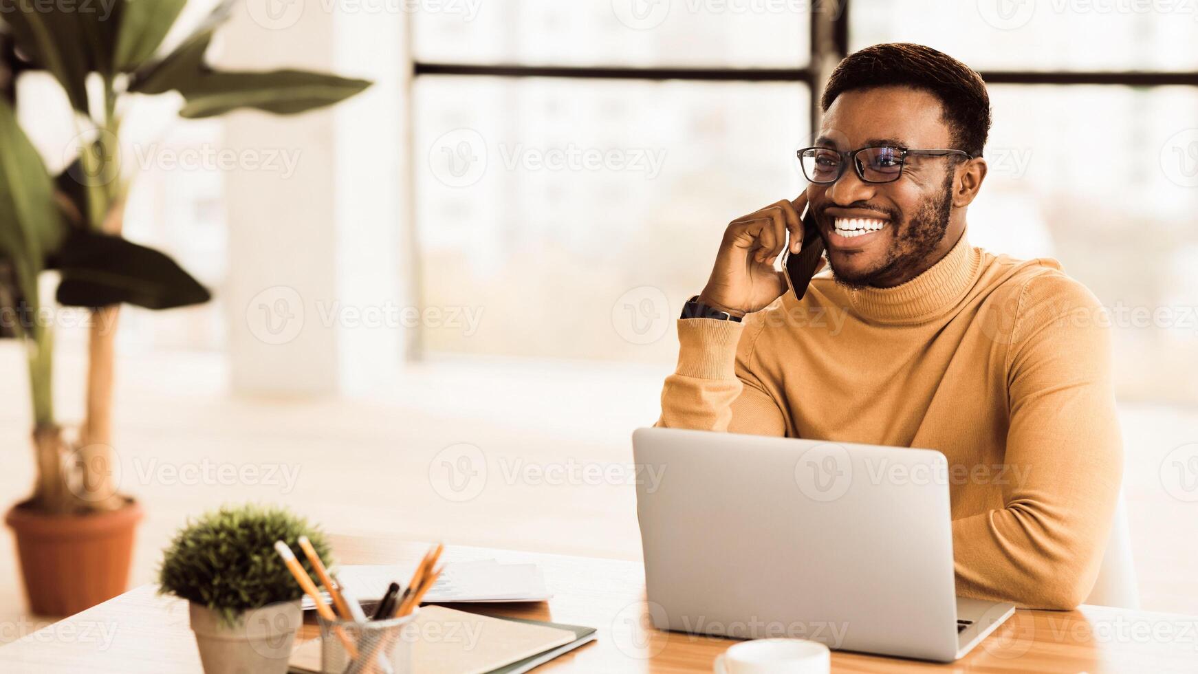 comunicación concepto. contento afro hombre hablando en móvil teléfono en moderno oficina. panorama con Copiar espacio foto