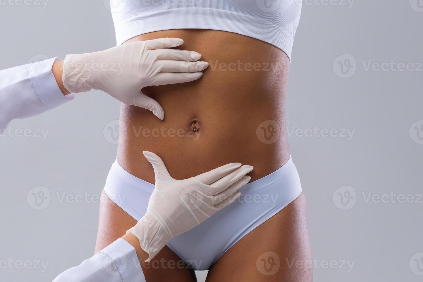 Cropped of plastic surgeon hands checking afro woman belly before beauty procedure, liposuction concept photo