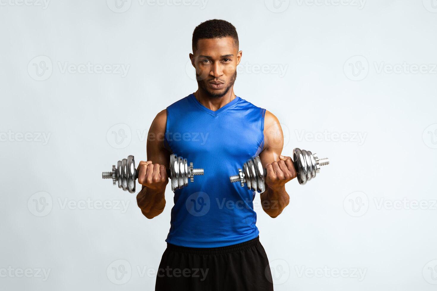 Hard Strength Workout. Determined black bodybuilder exercising with dumbbells over yellow studio wall, copyspace photo