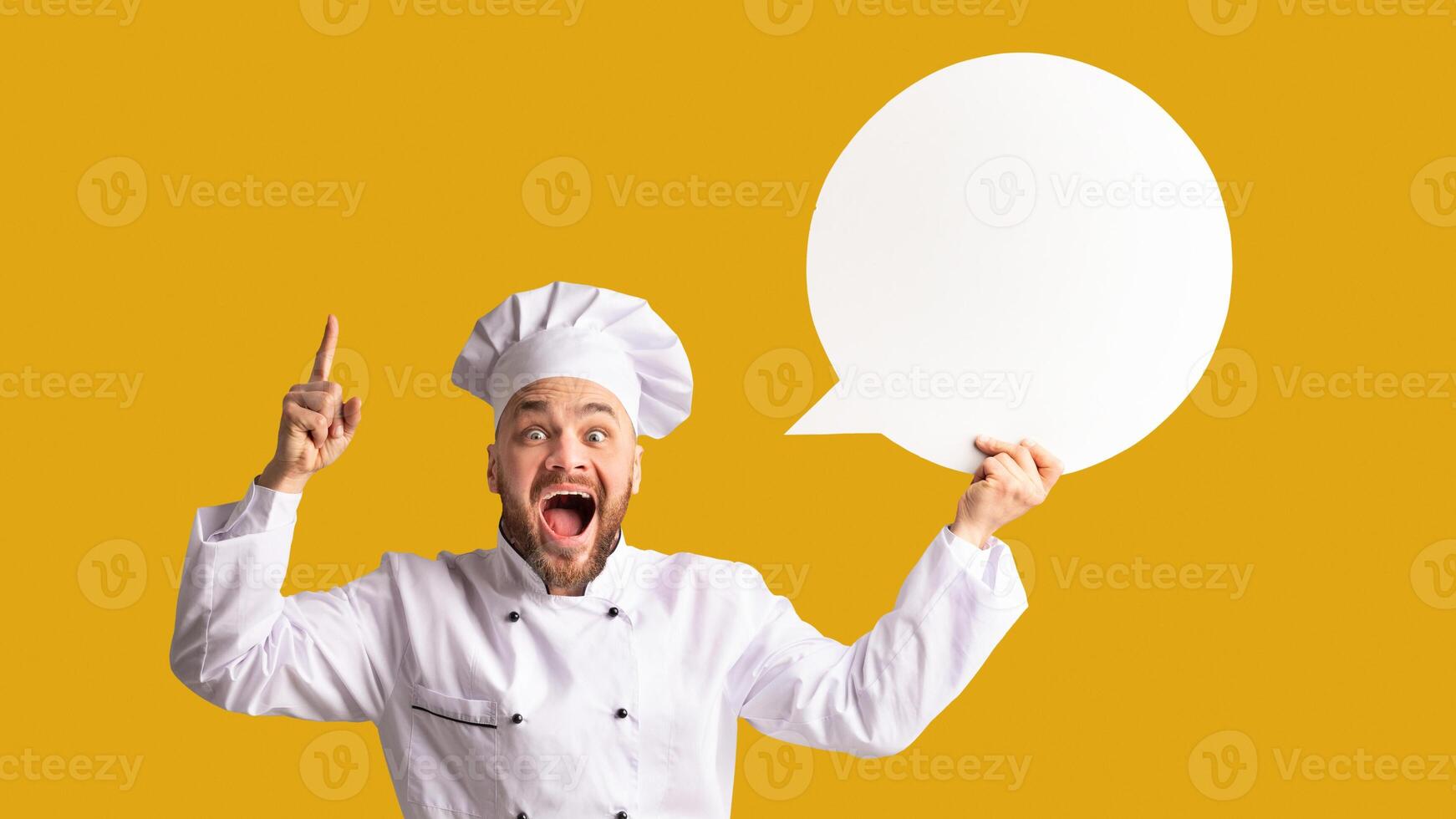 Recipe Idea. Excited Chef Man Holding Blank White Speech Bubble Pointing Finger Standing On Black Studio Background. Panorama, Mockup photo