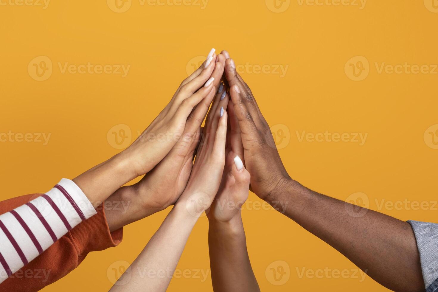 The image showcases multiple hands of various skin tones reaching upwards and touching in a gesture of unity and collaboration, cropped photo