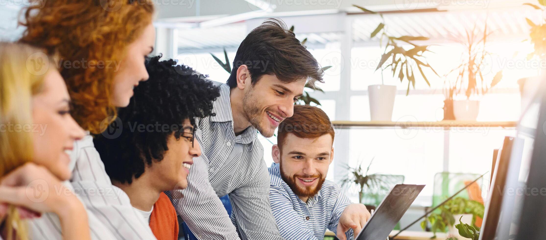 New business plan. Young cheerful people looking at clipboard at coworking workplace, free space photo