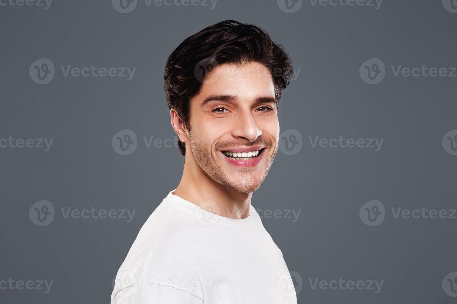 Semi profile portrait of cheerful caucasian guy on grey background photo