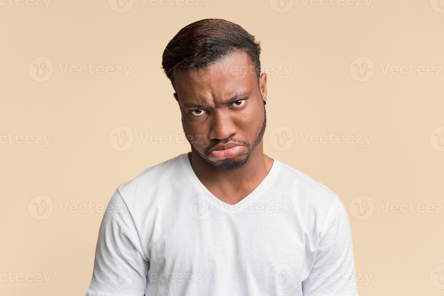Sulky Face. Grumpy Afro Guy Looking At Camera Posing Over Yellow Background. Studio Shot photo