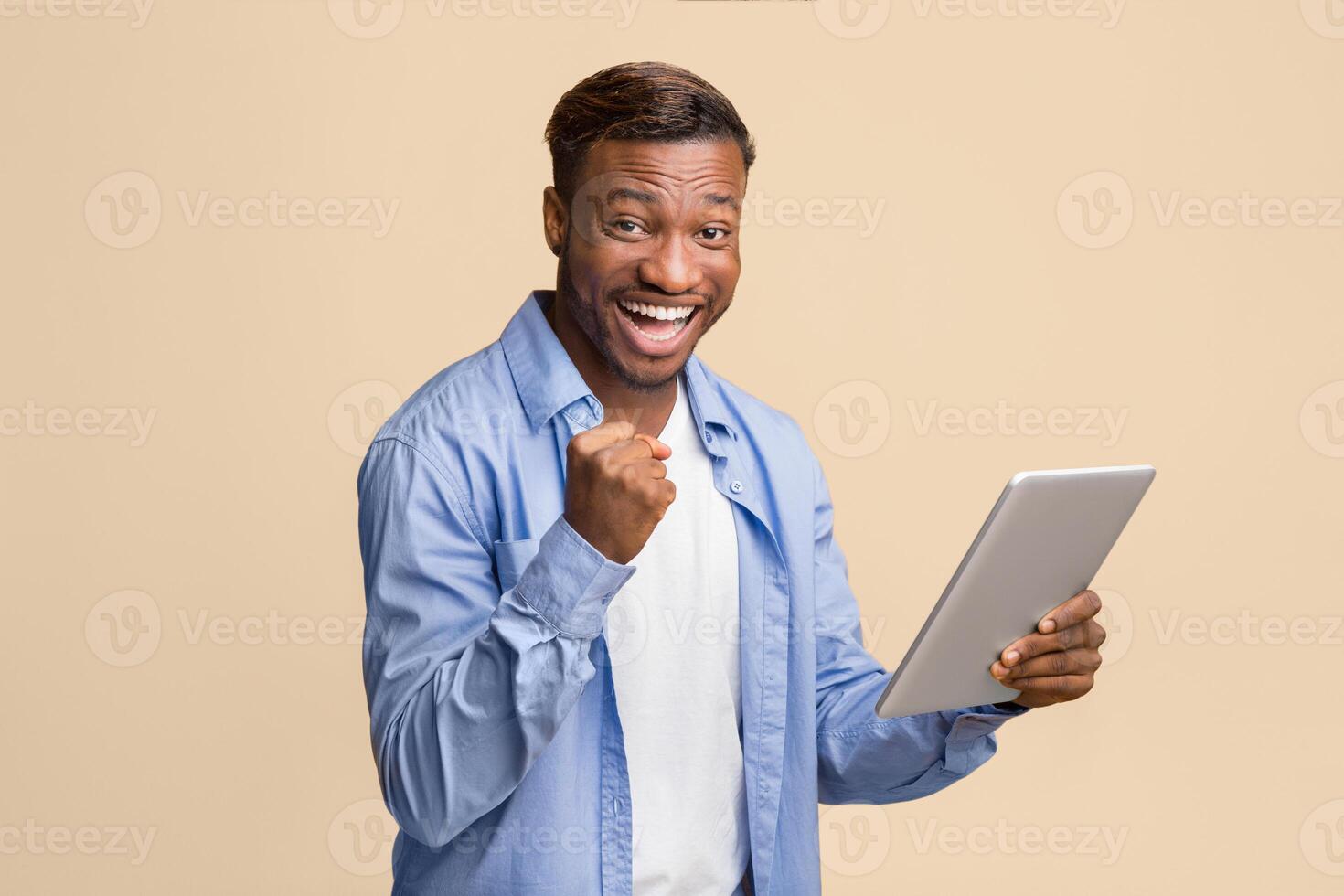 Cheerful African American Guy Holding Digital Tablet Gesturing Yes Standing On Yellow Background. Studio Shot photo