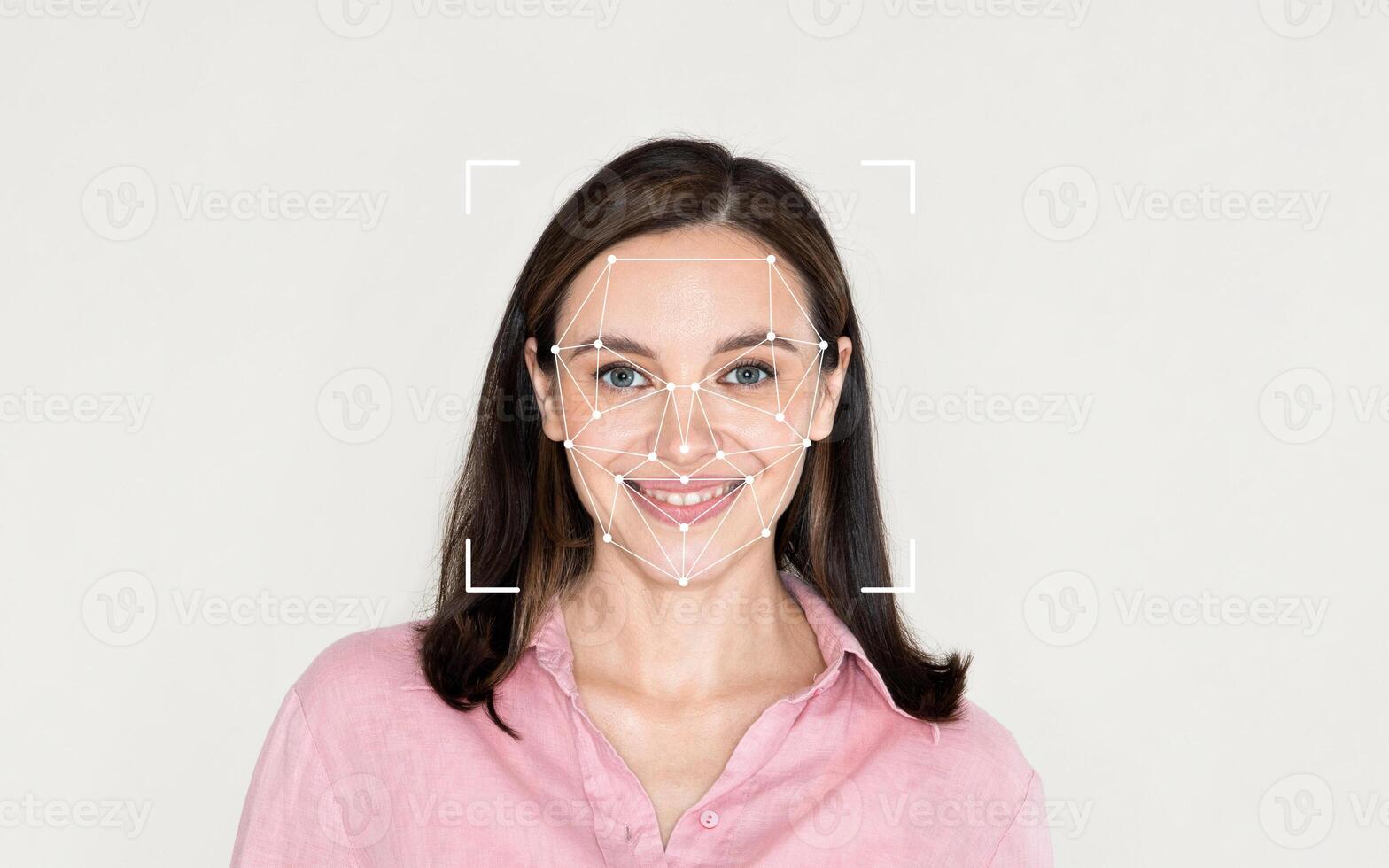 A woman smiles while facial recognition technology maps her features in a plain environment. photo