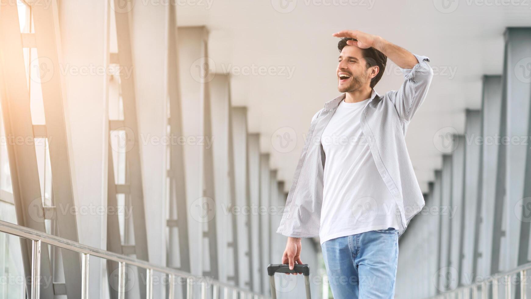 Looking forward to new places. Cheerful man walking with luggage at airport, ready for boarding on his flight, free space photo
