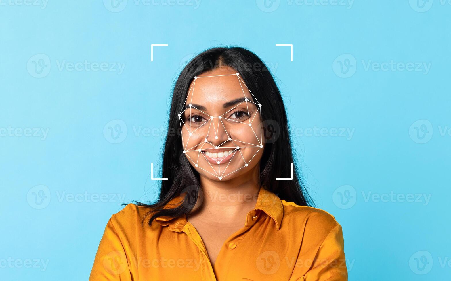 Indian woman smiles confidently with facial recognition patterns displayed on her face, set against a bright blue backdrop. photo