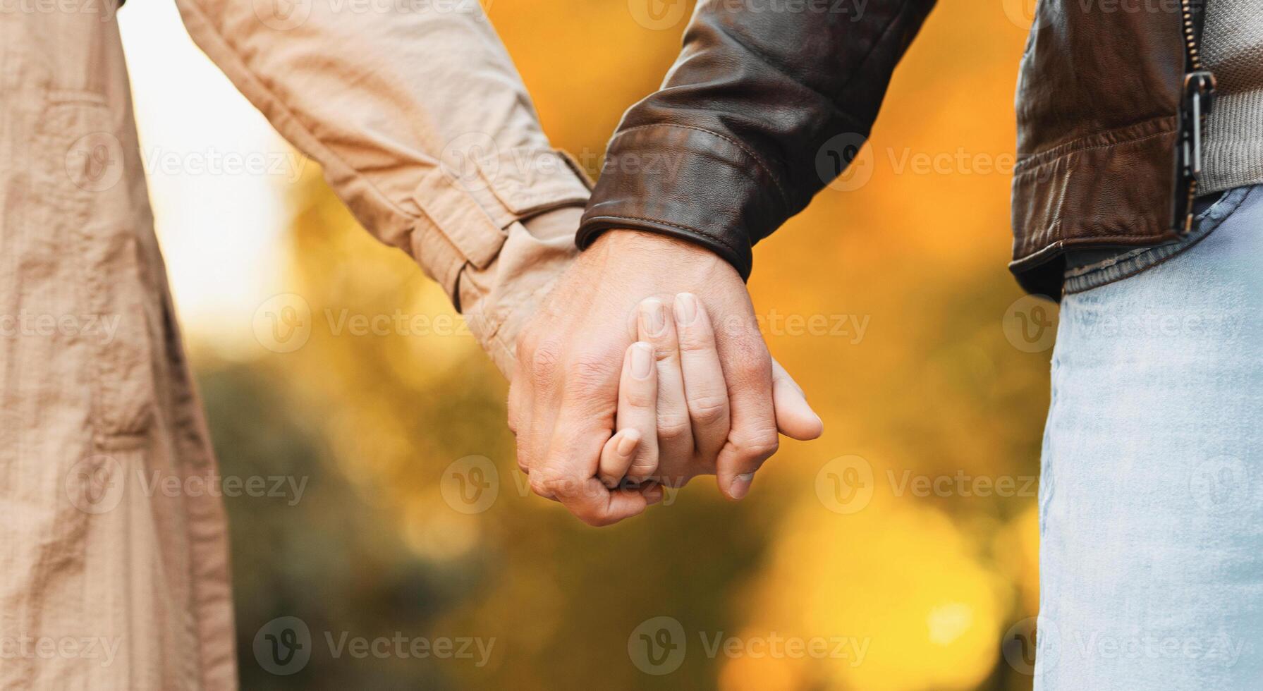 Hands of couple walking by autumn forest, cropped photo